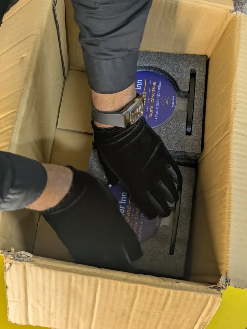 Gloved hands handling the property-branded GolTap standees inside their packaging
